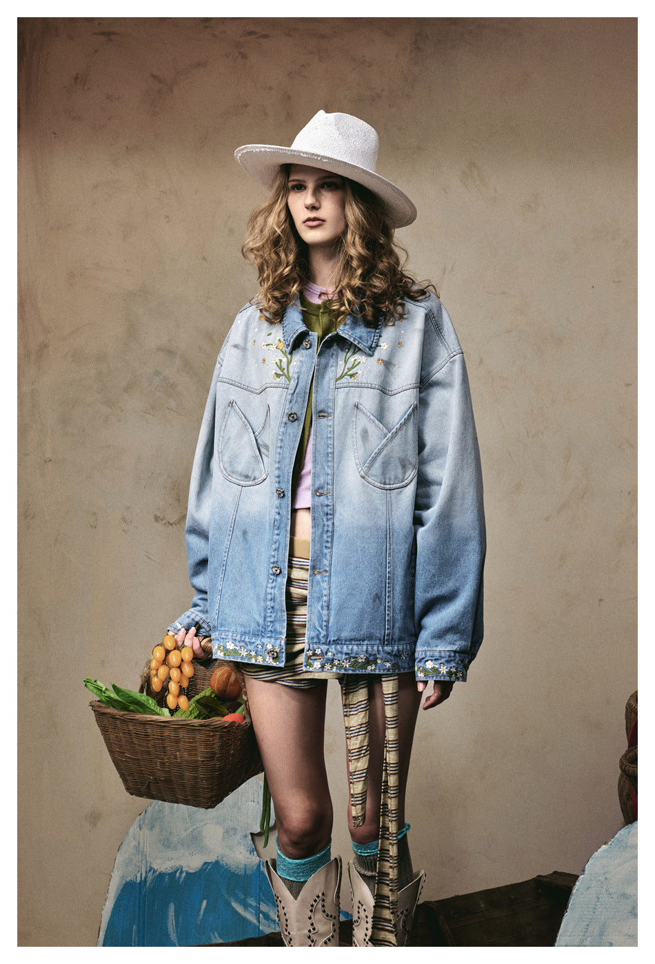 Three-quarter front view of a model wearing a light blue jacket with floral embroidery and oversized pockets.