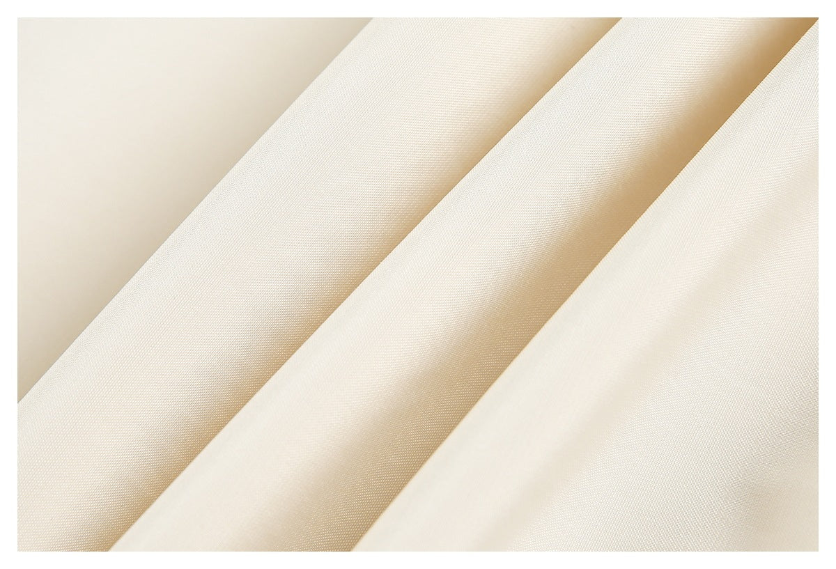 Close-up of ivory fabric arranged in diagonal folds, showing a fine, subtle weave.