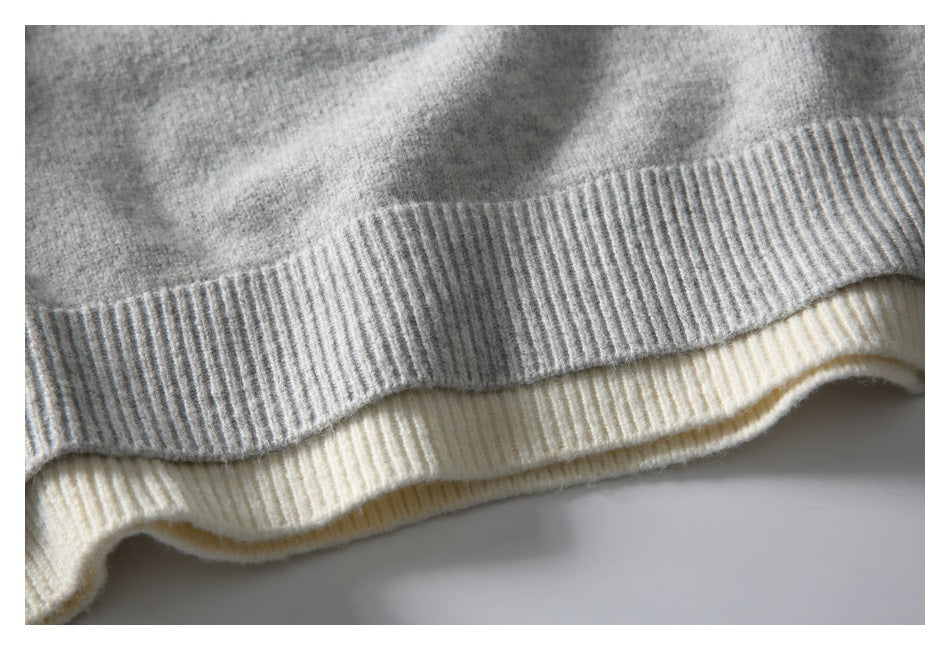 Close-up of a gray knit sweater hem layered over a cream ribbed hem.
