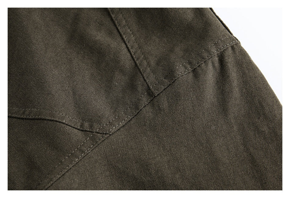 Close-up of olive-brown jacket fabric with intersecting stitched seams.