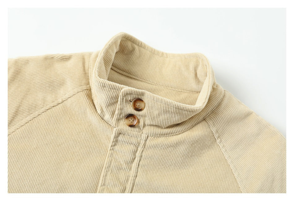 Close-up of a beige jacket's ribbed stand collar with two brown buttons and raglan shoulder seams.