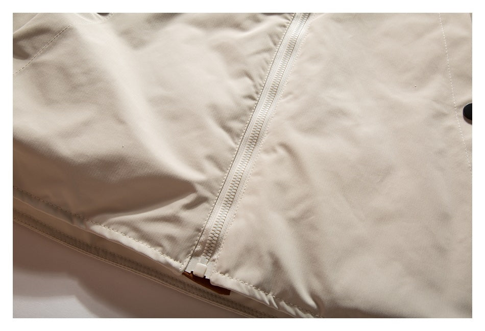Close-up of a beige garment’s zipper and stitched front panel.