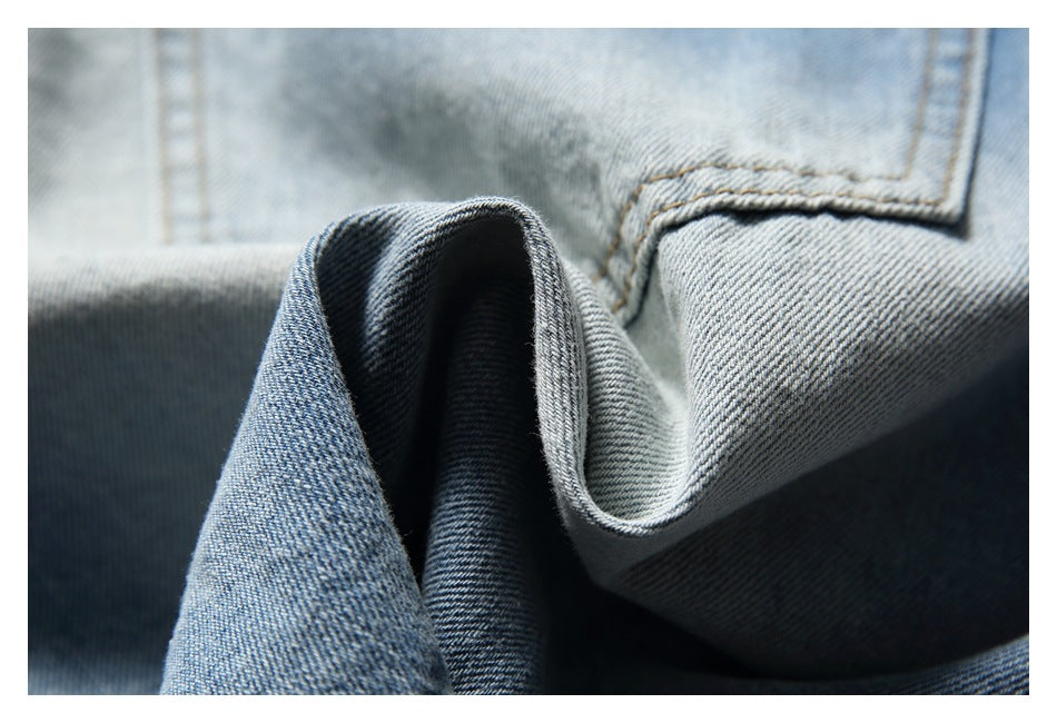 Close-up of folded light-wash denim showing its diagonal weave and stitched seams.