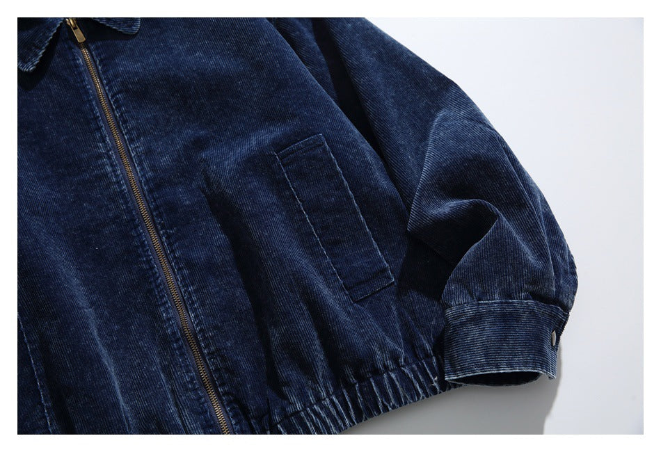 Cropped view of a dark navy corduroy jacket with a brass zipper, chest pocket, and elasticated hem.