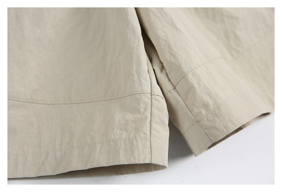 Close-up of light beige garment hems with visible stitching and a softly textured surface.