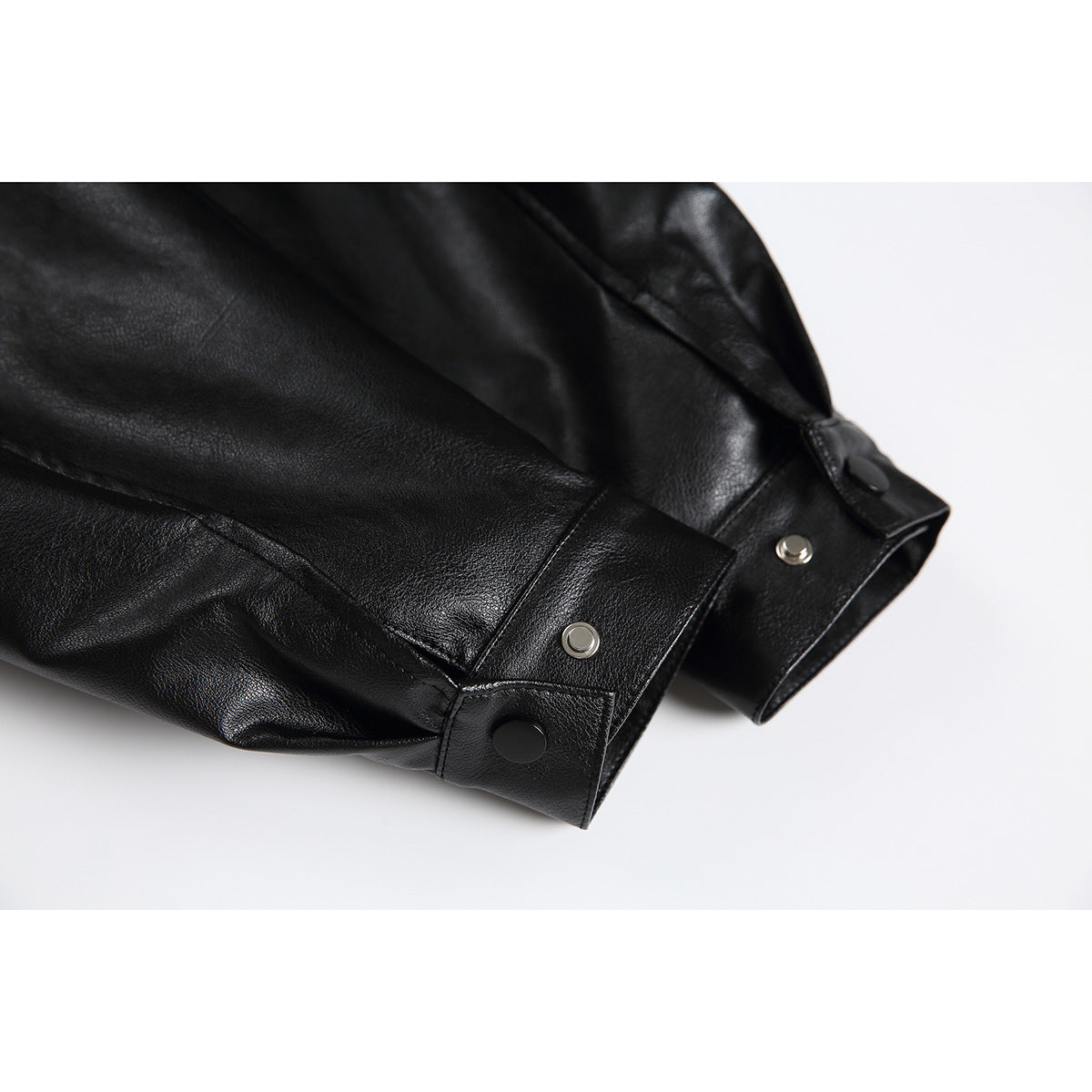 Close-up of a black jacket sleeve cuff with snap buttons and visible stitching.