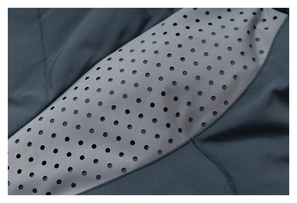 Close-up of a jacket's curved gray panel with rows of perforations, bordered by dark slate fabric.