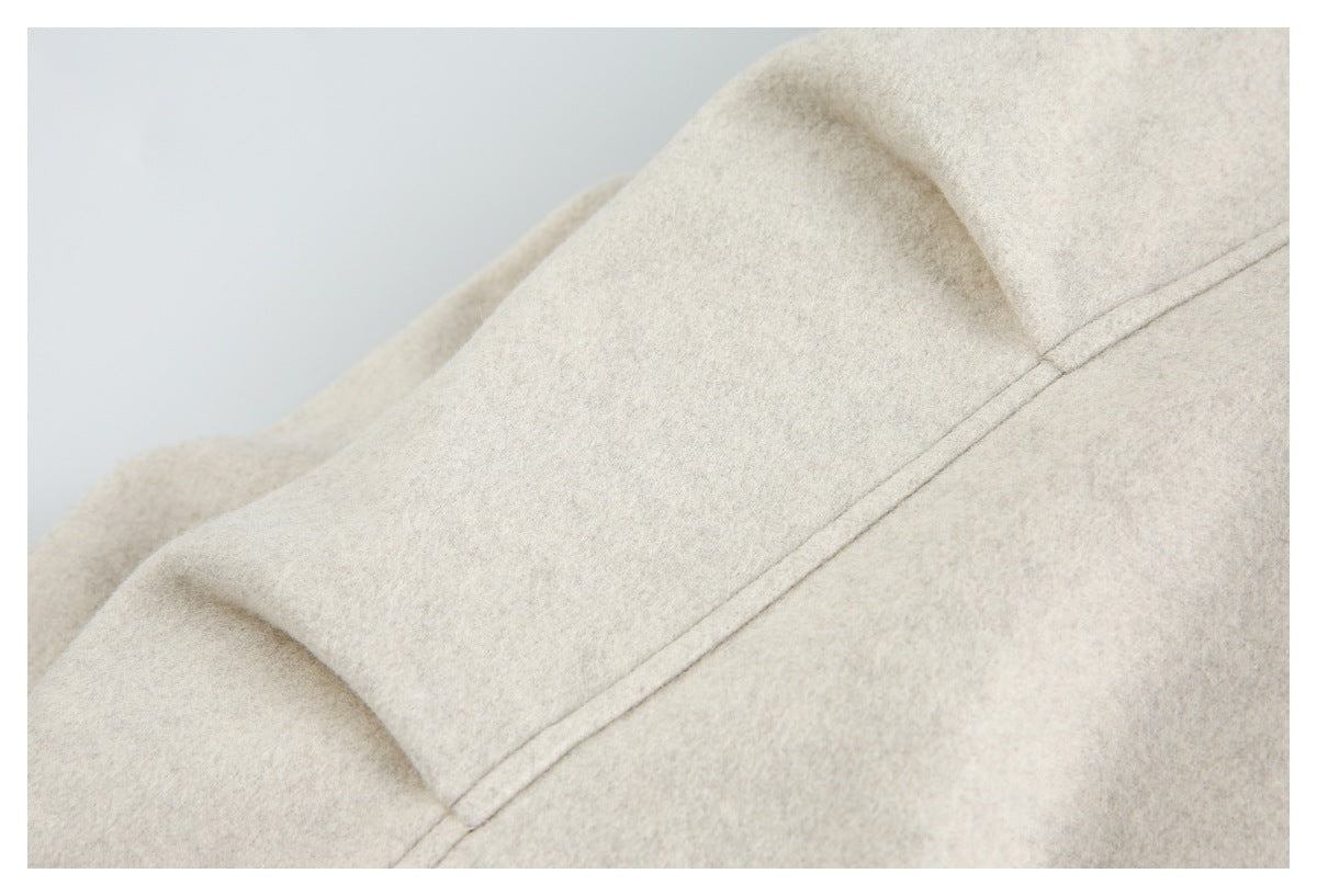 Close-up of a pale beige jacket panel with a curved seam and visible stitching.