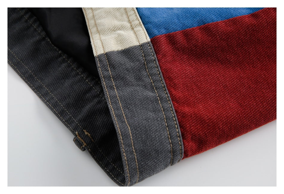 Close-up of stitched charcoal, cream, blue, and red panels along a folded garment edge.