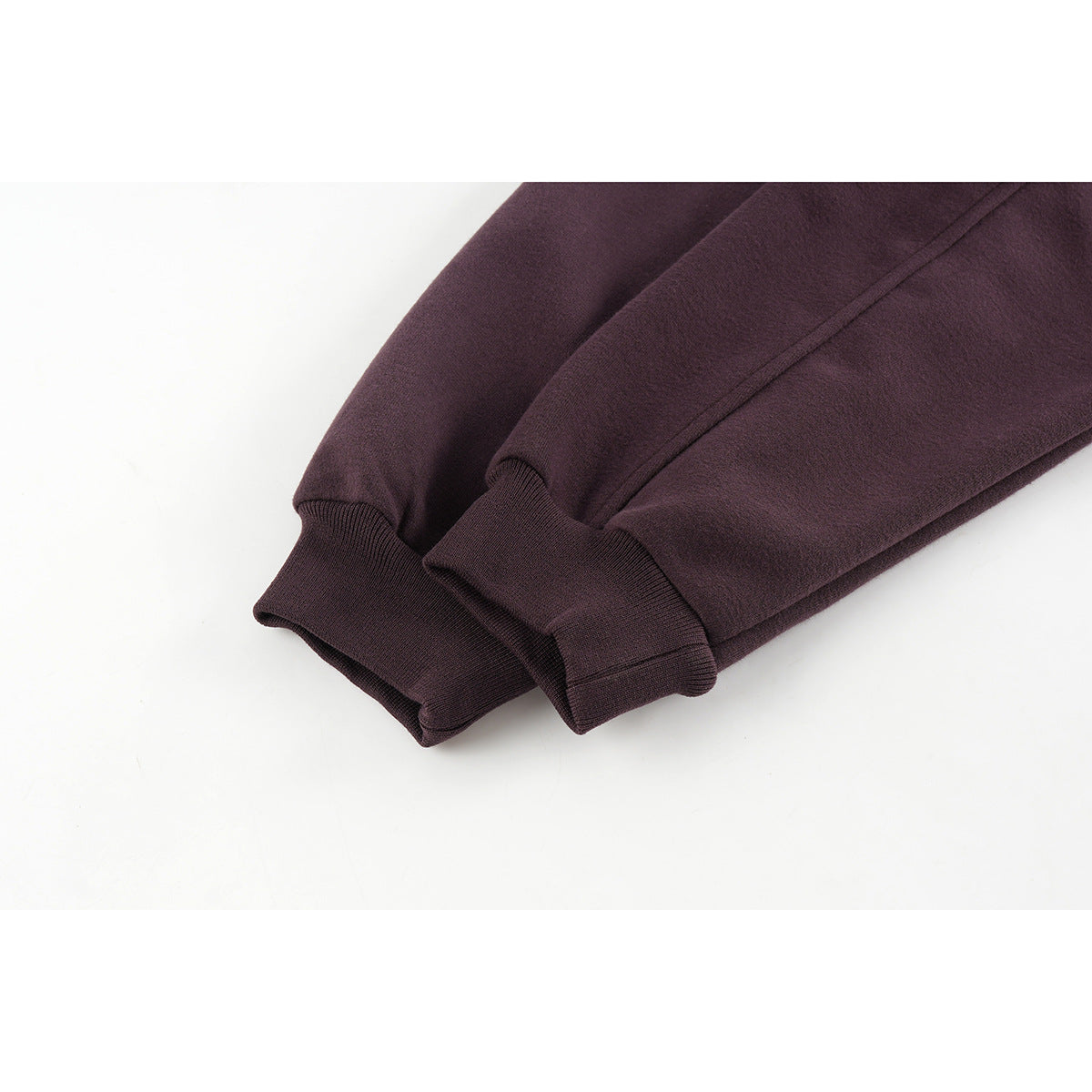 Close-up of the plum jacket's sleeves with gathered rib-knit cuffs and curved seam detailing.