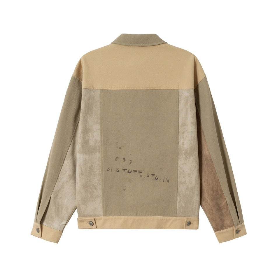 Back view of a color-block jacket in tan, taupe and pale beige, with printed distressed-style marks.