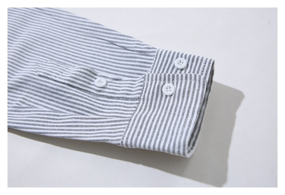 Close-up of a white shirt sleeve with fine gray stripes and a buttoned cuff.