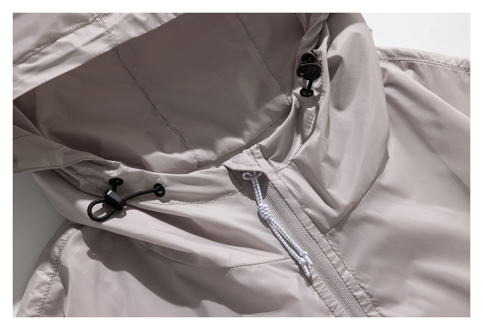 Close-up of a light taupe jacket hood with black adjustment toggles and a pale zipper.