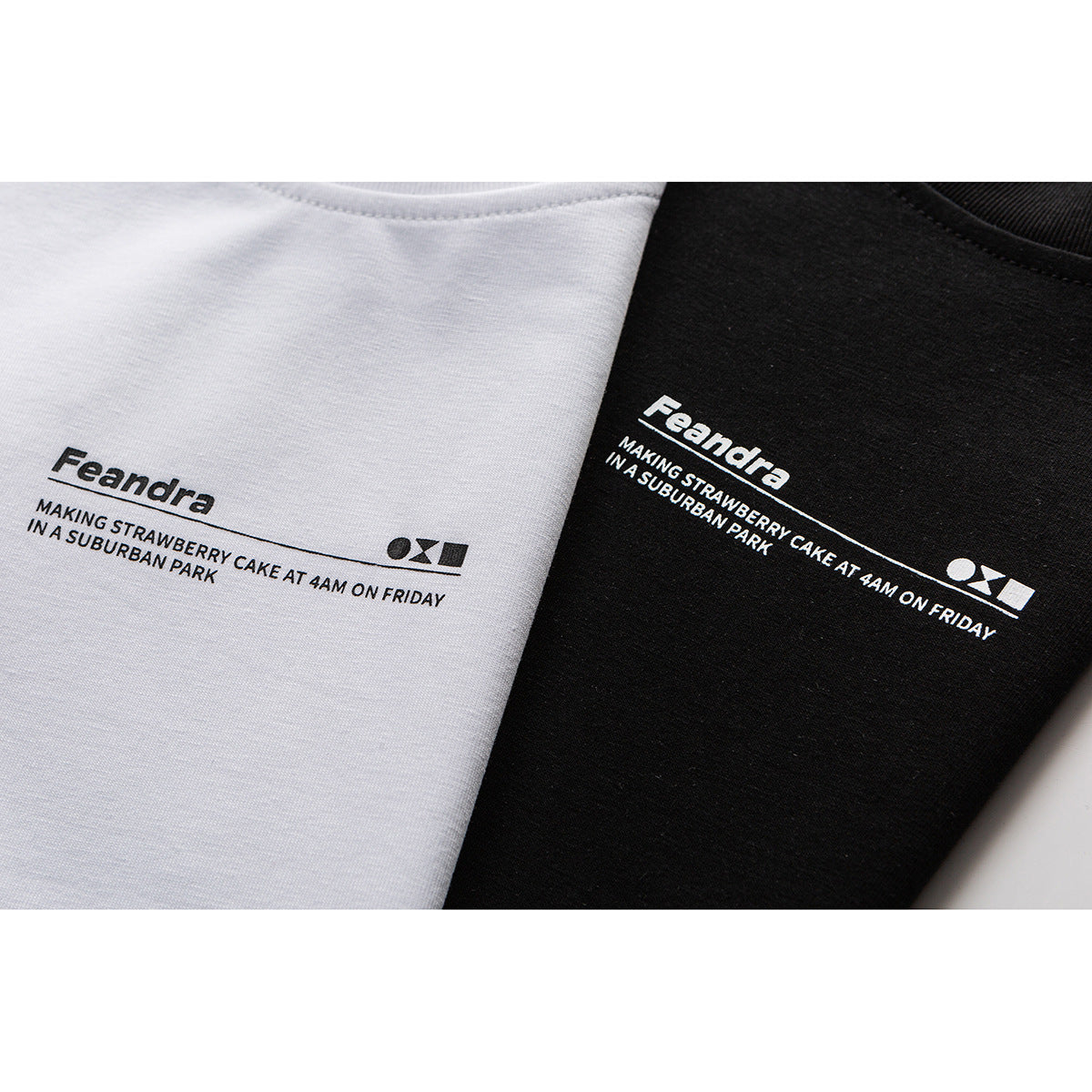 Close-up of white and black T-shirts with printed “Feandra” text and a slogan.