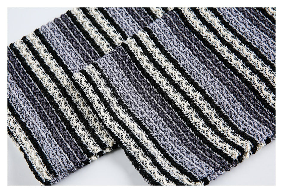Close-up of folded edges and striped open-knit fabric in black, charcoal, and ivory.