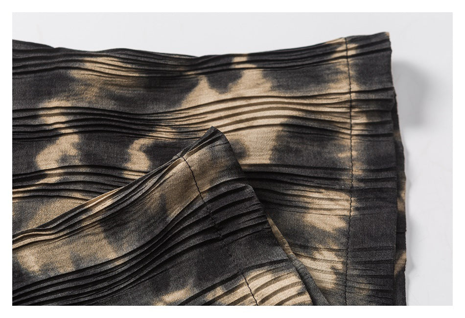 Close-up of the printed, pleated garment showing a folded edge and stitched seam.