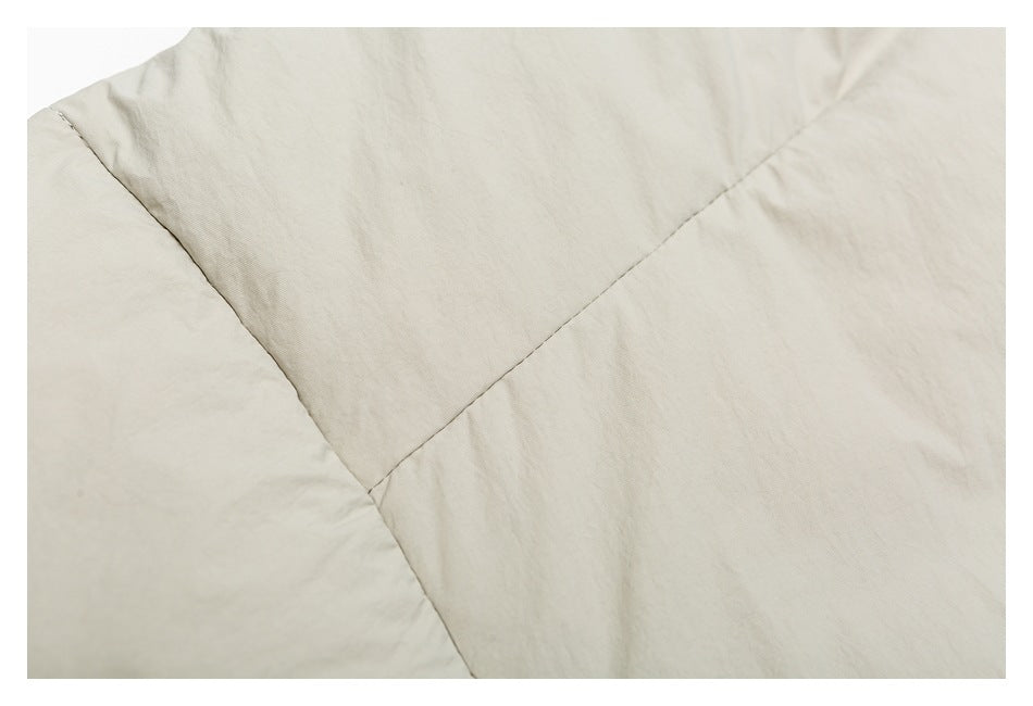 Close-up of pale beige garment fabric with curved and diagonal stitched seams.