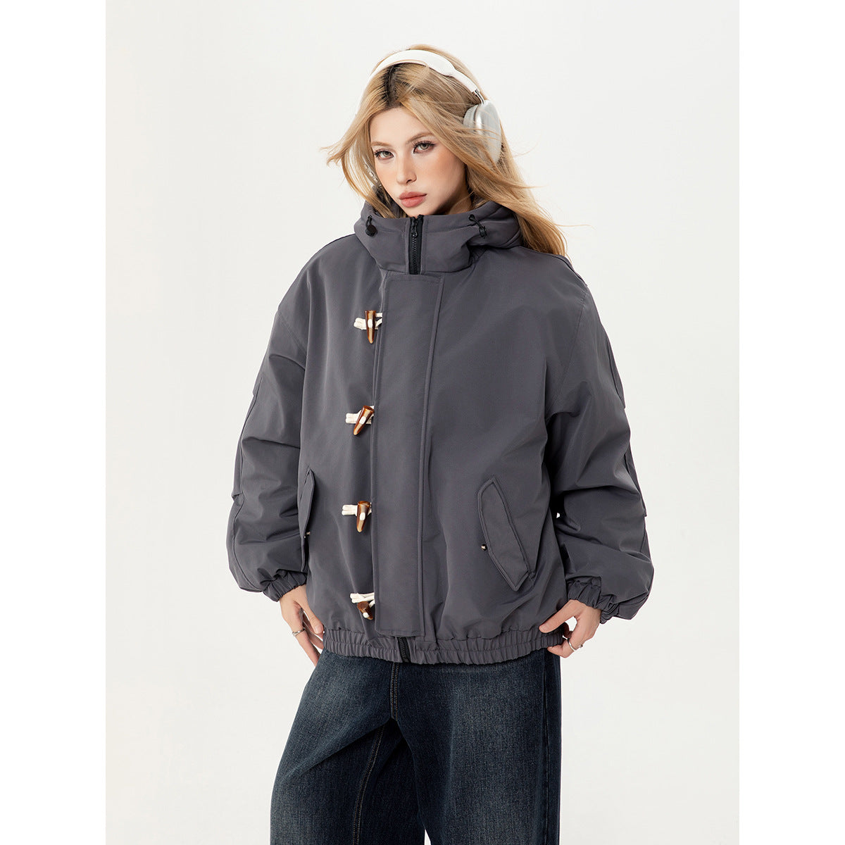 Model wearing a charcoal gray hooded jacket with toggle closures, angled pockets and an elastic hem.