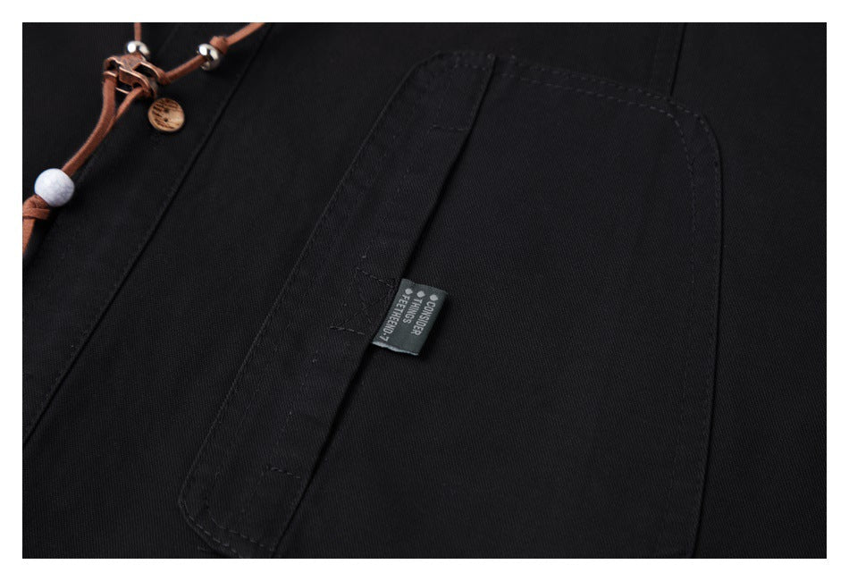 Close-up of a black garment pocket with a small sewn label and a brown cord necklace with beads.