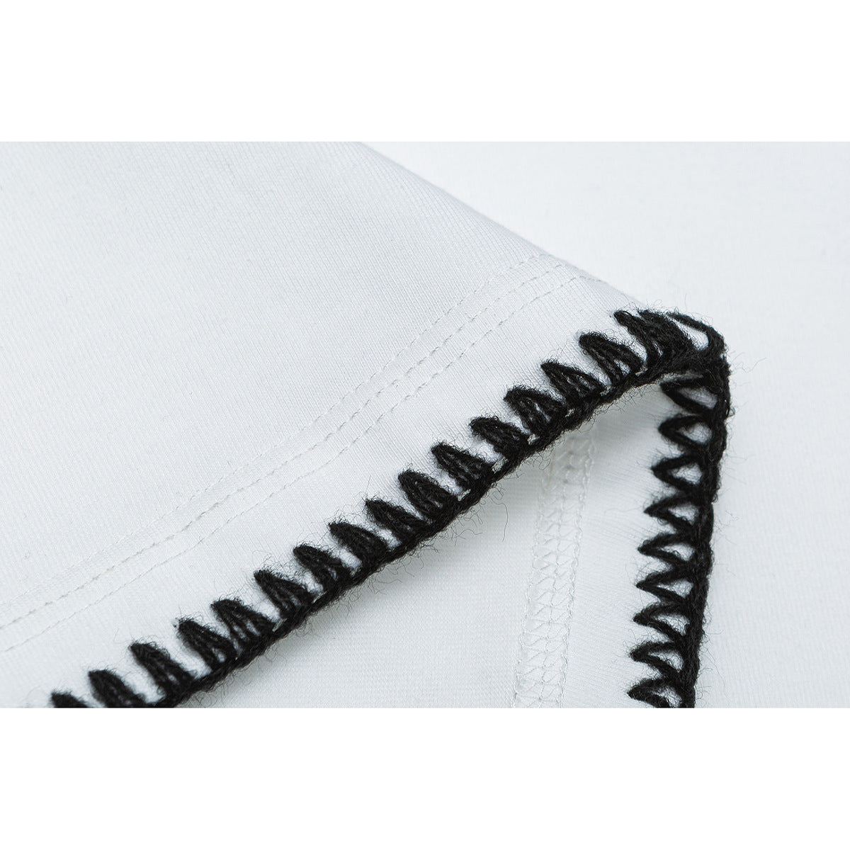 Close-up of a white T-shirt seam with thick black blanket stitching.
