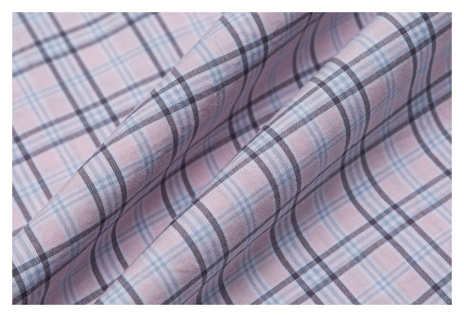 Close-up of pale pink plaid fabric folded to show its pattern and surface.