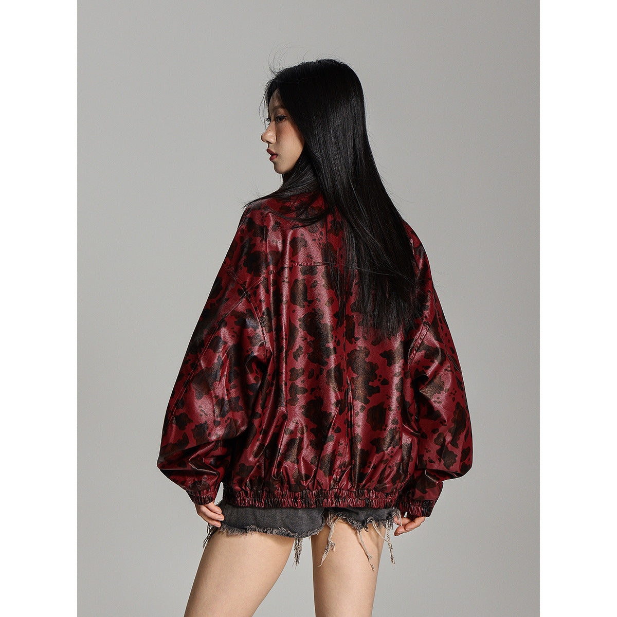 Rear view of a model wearing the burgundy mottled jacket with a gathered elastic hem and cuffs.