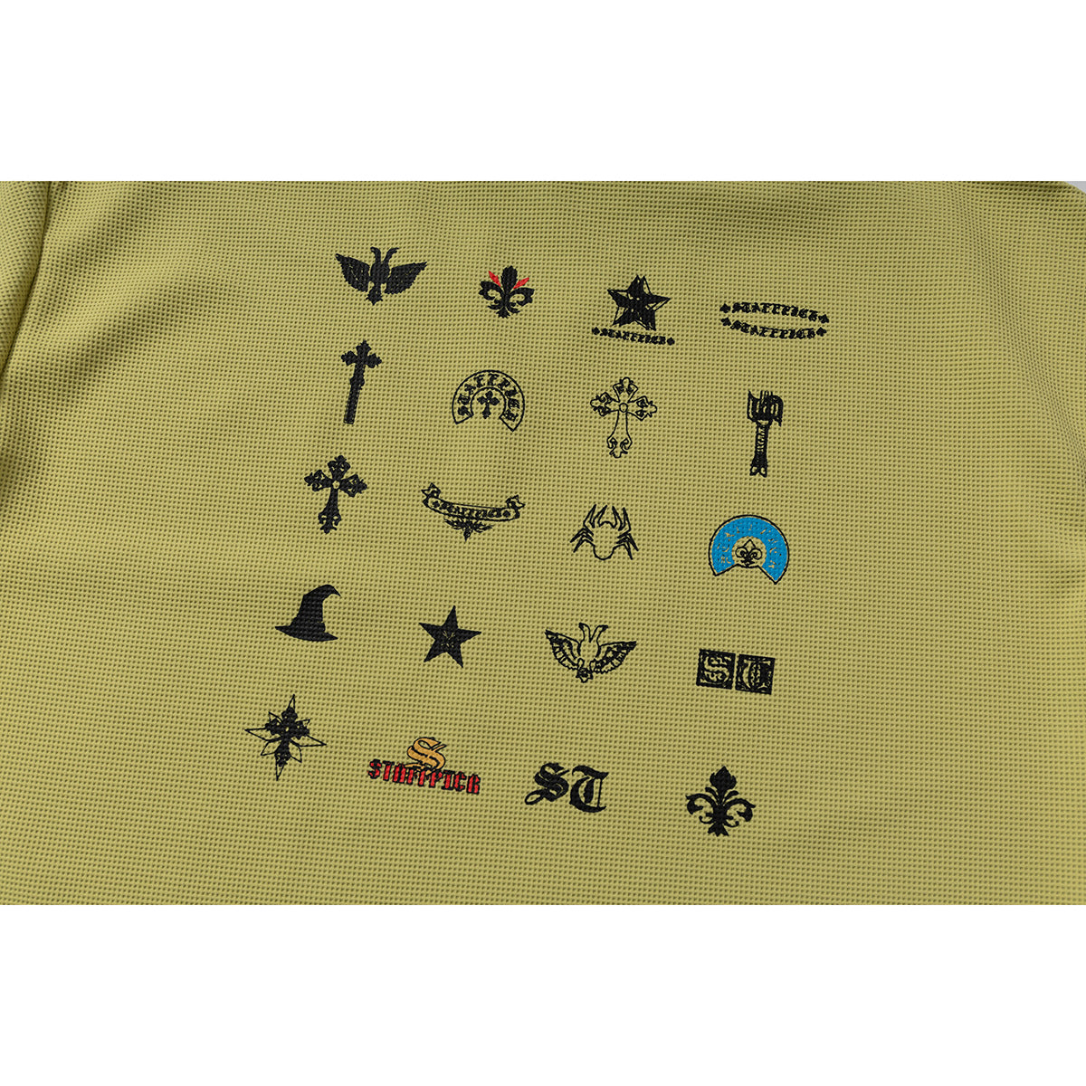 Close-up of assorted black decorative symbols and lettering printed on muted olive-yellow fabric.