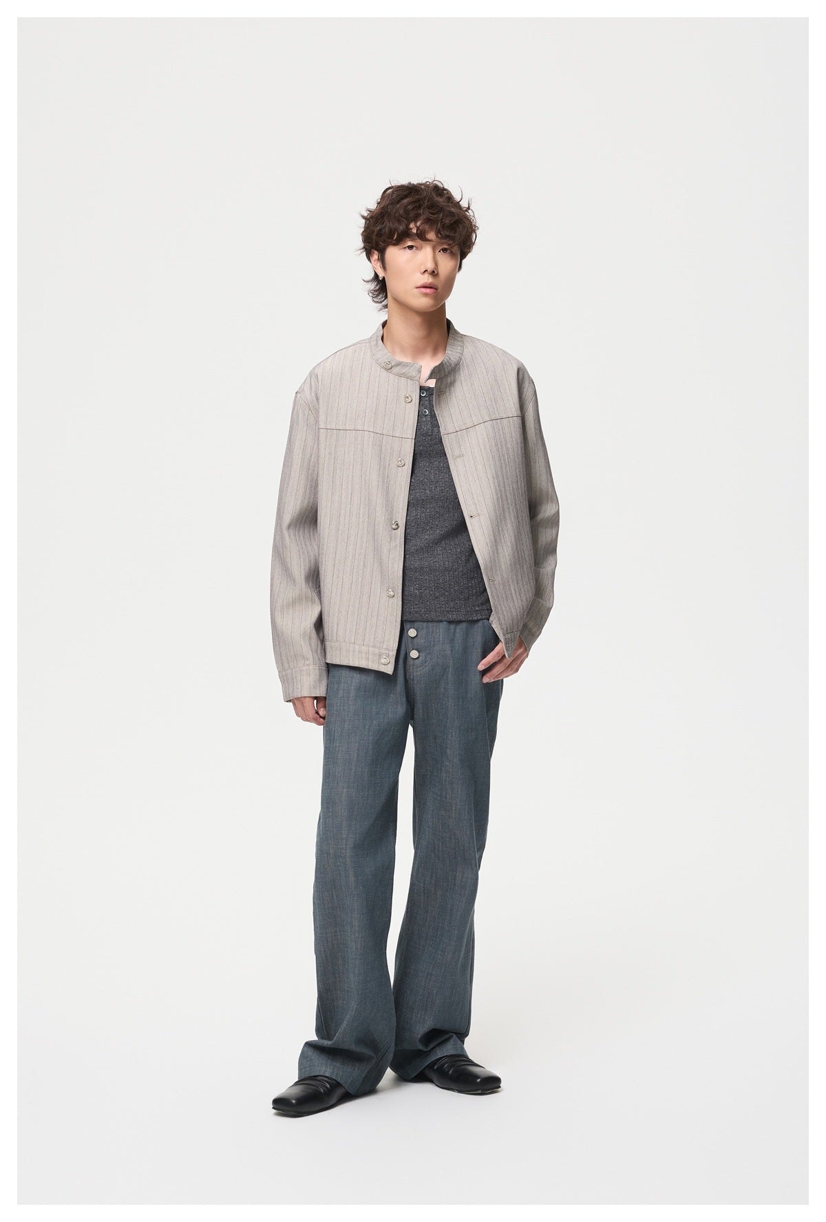 Model wearing gray striped stand-collar jacket open over a dark gray top and blue-gray wide-leg pants, front view