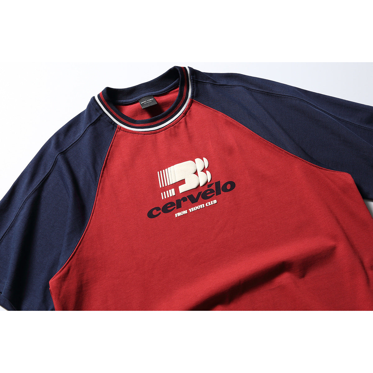 Close-up of a red-and-navy raglan T-shirt with striped ribbed collar and cream-and-navy chest graphic.