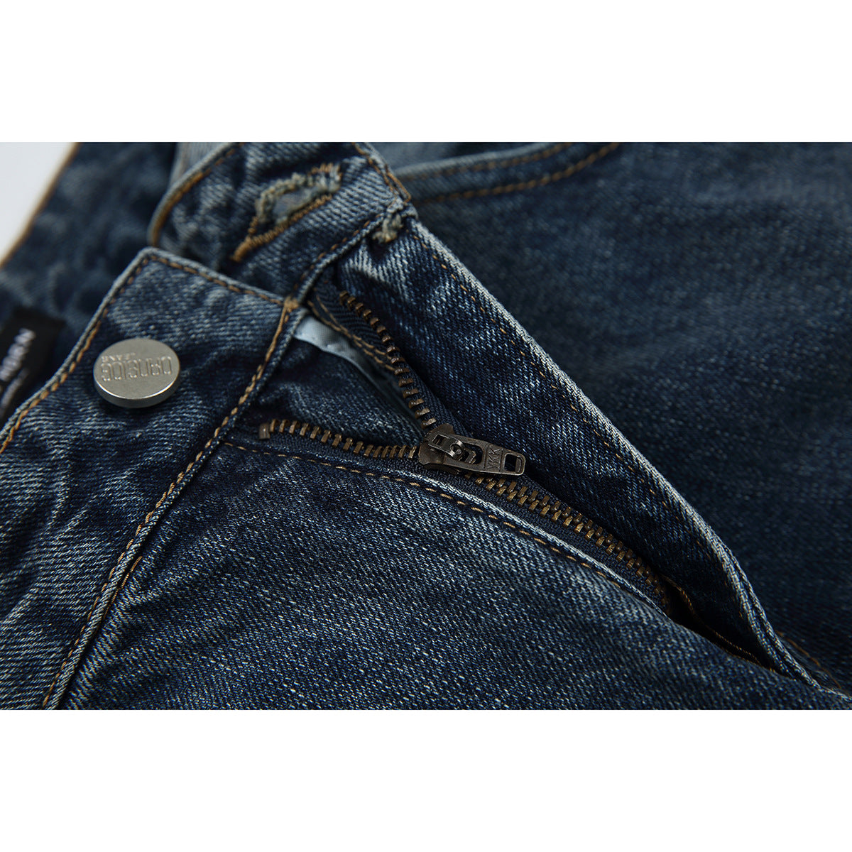 Close-up of dark blue jeans with the fly unzipped, showing the metal zipper and button.