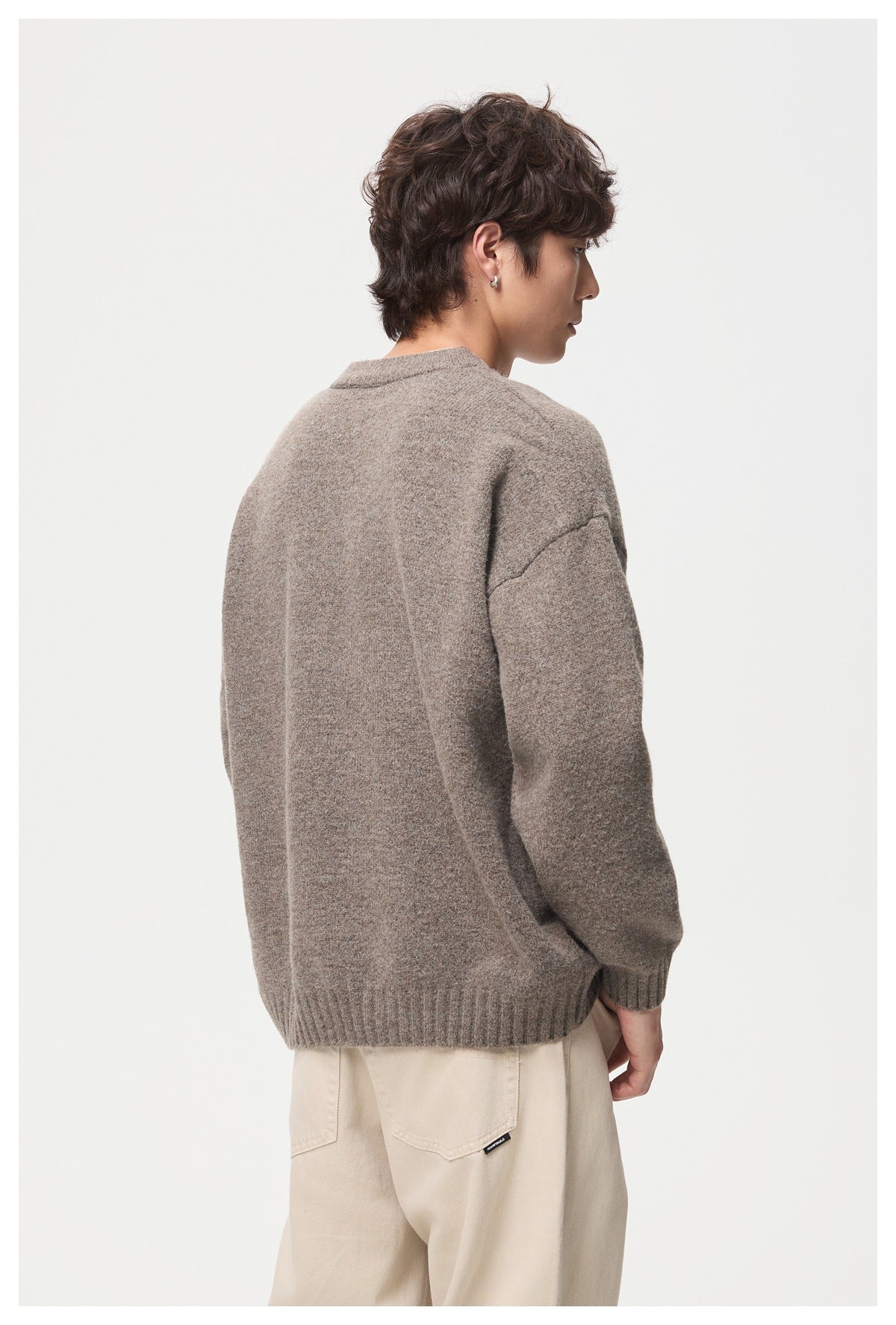 Rear view of a model wearing a taupe oversized sweater with ribbed hem and cuffs.