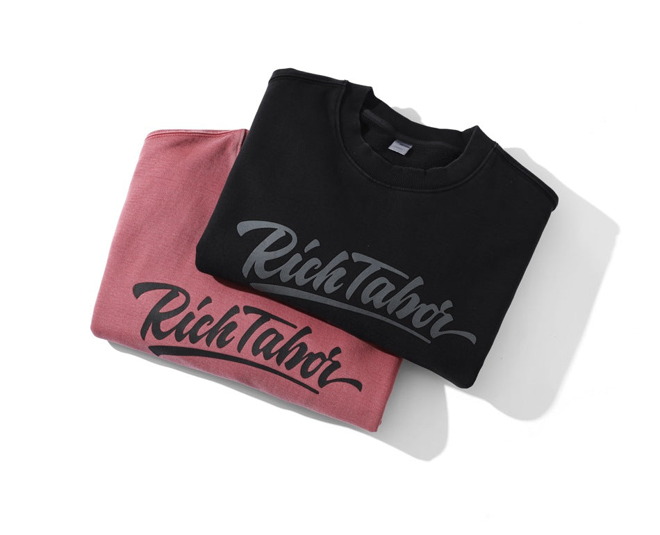 Two folded crewneck sweatshirts, one black and one dusty rose, each with large script chest print.