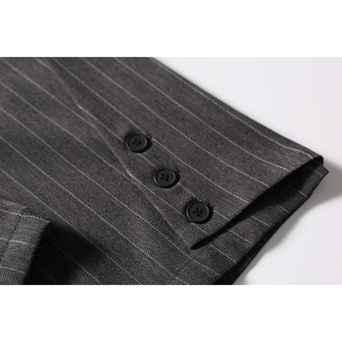 Close-up of a trouser leg hem with three black buttons and fine pinstripes.