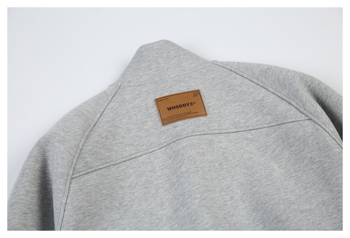 Close-up of the back of a light gray sweatshirt with a brown rectangular sewn patch.