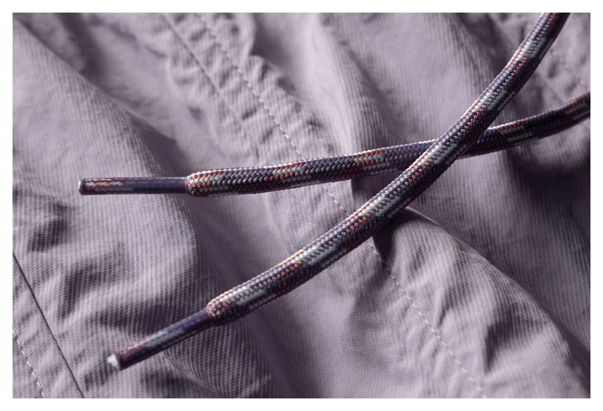 Close-up of the pants' braided multicolor drawcords against lavender fabric.
