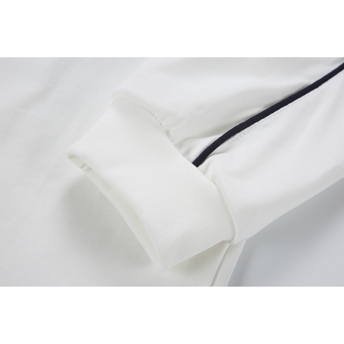 Close-up of a white long-sleeve shirt cuff and sleeve with narrow dark piping.
