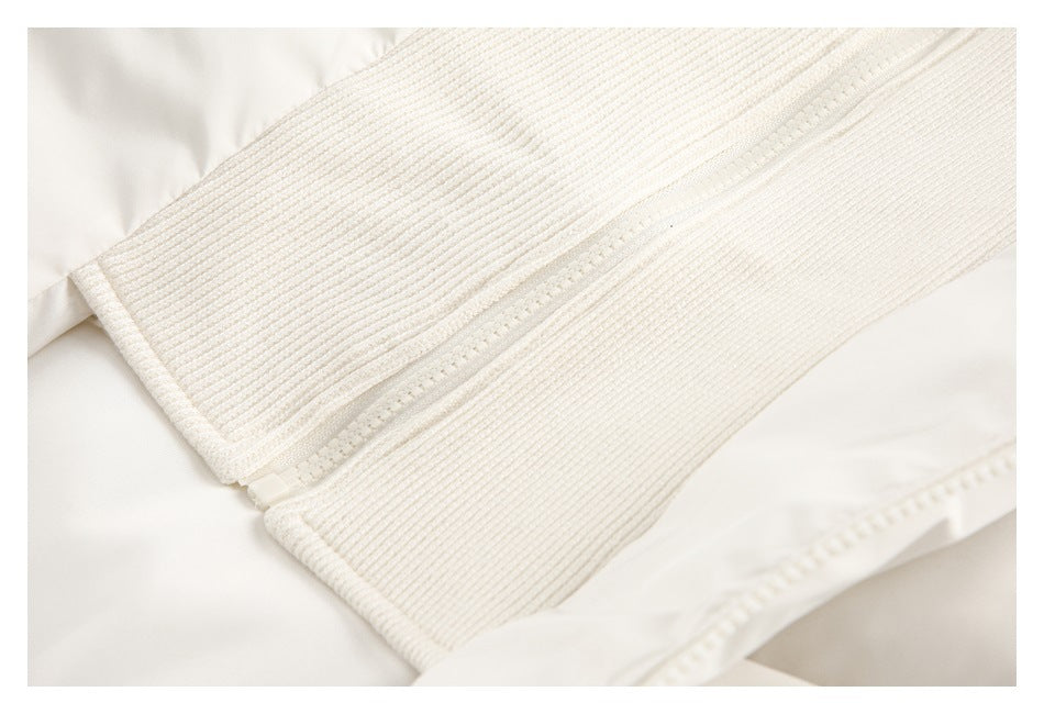 Close-up of an off-white zipper running along wide ribbed knit trim on a garment.