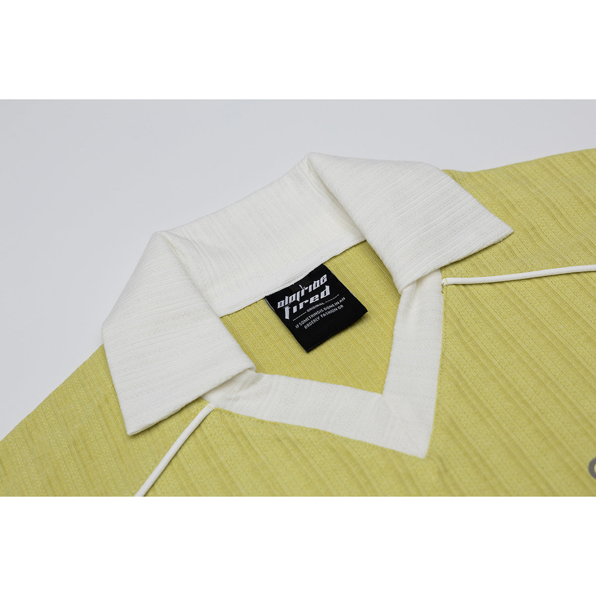 Close-up of a lime-yellow shirt collar with white trim and a black neck label.