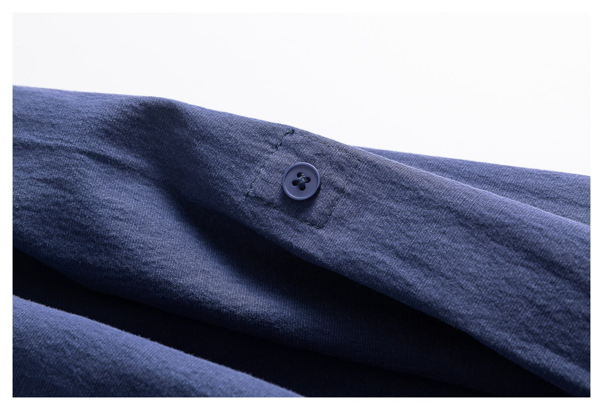 Close-up of a blue shirt sleeve with a single dark button on a narrow button tab.