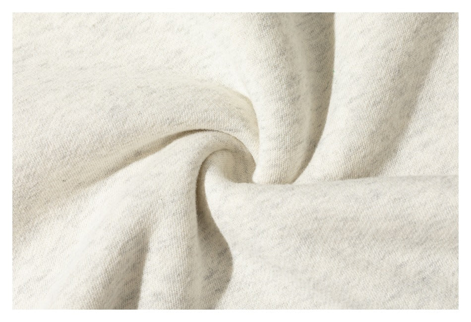 Close-up of lightly heathered cream sweatshirt fabric gathered into soft folds.