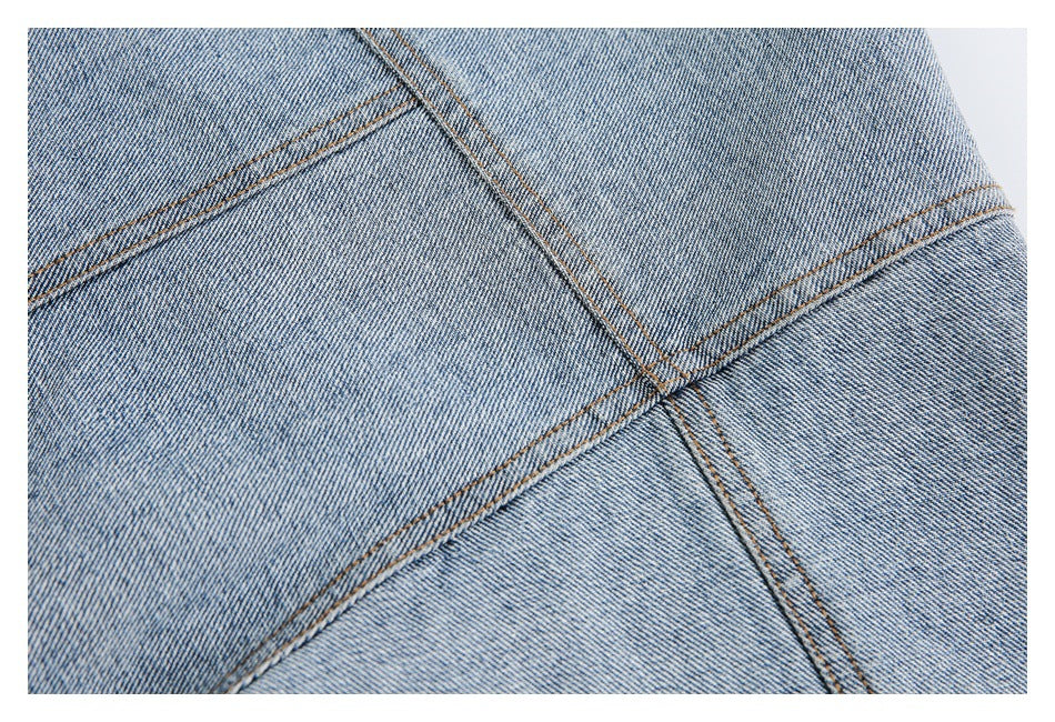 Close-up of light blue denim panels meeting at intersecting seams with tan stitching.