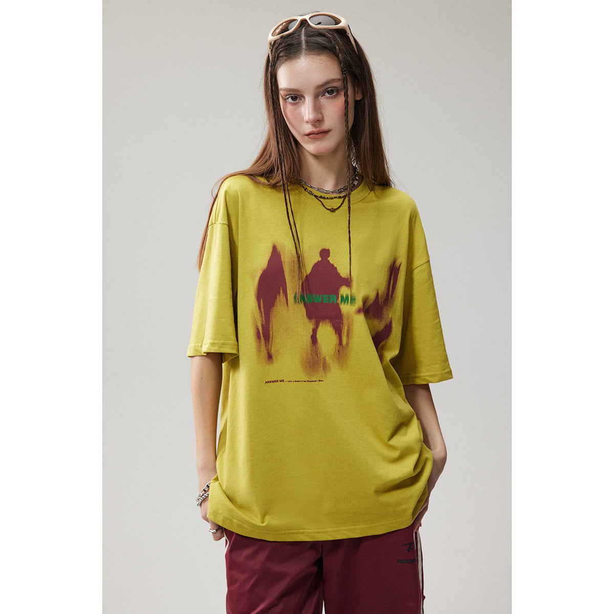 Model wearing an oversized yellow graphic T-shirt with burgundy pants.