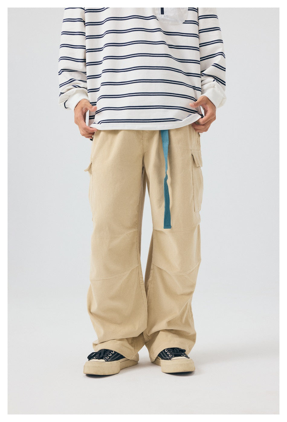 Front view of loose beige cargo pants with a blue drawstring, worn with a white and navy striped top.