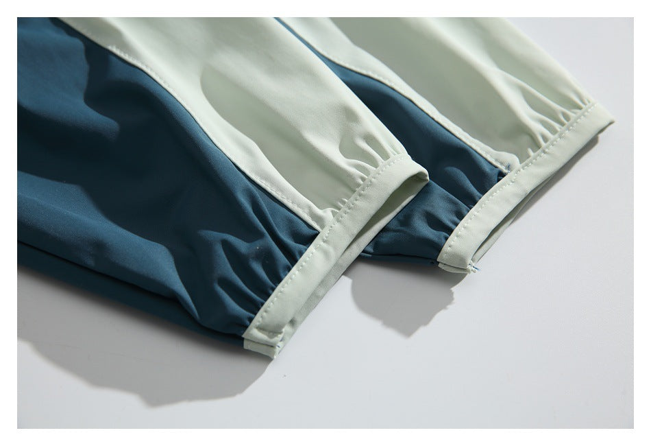 Close-up of two pale stitched hems on a dark teal and ivory color-block garment.
