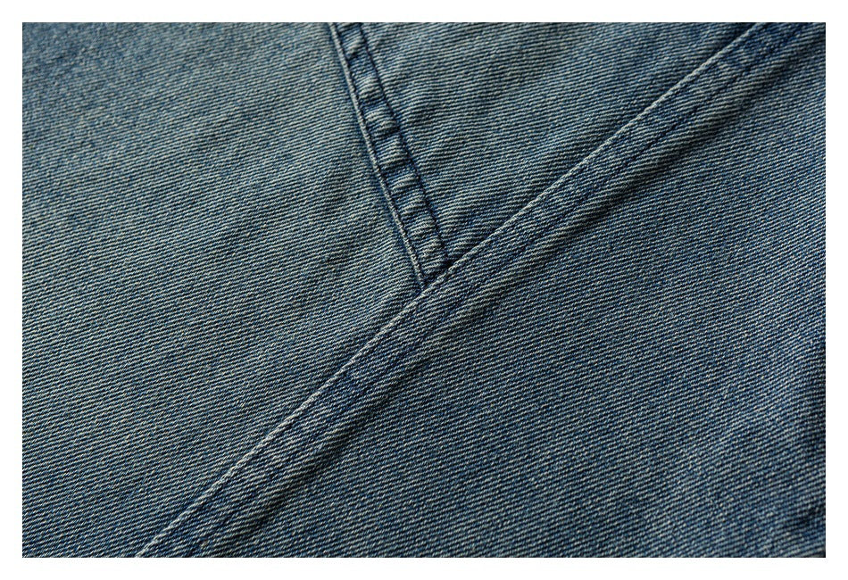 Close-up of blue denim with a diagonal double-stitched seam crossing another seam.
