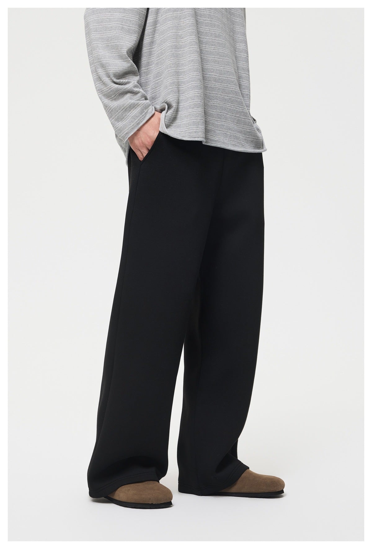 Front view of a person wearing black wide-leg pants with a gray striped top and brown shoes.