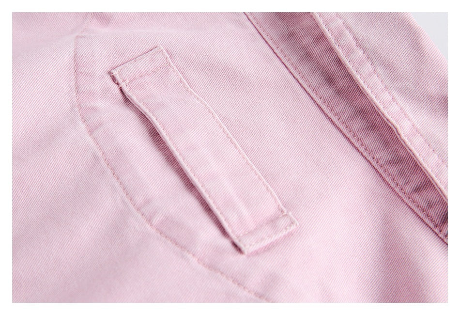 Close-up of pink garment fabric with a stitched rectangular pocket flap and seam.