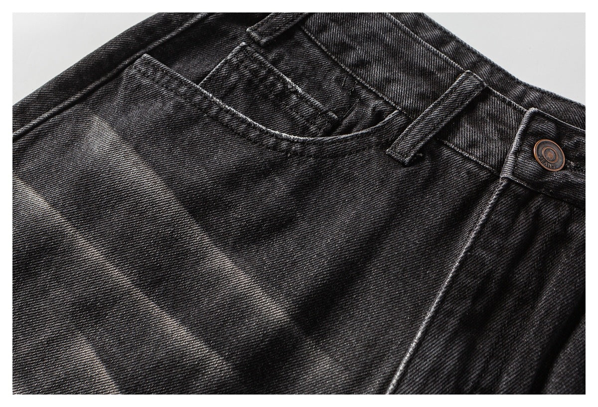 Close-up of a curved front pocket and buttoned waistband on black washed denim shorts.