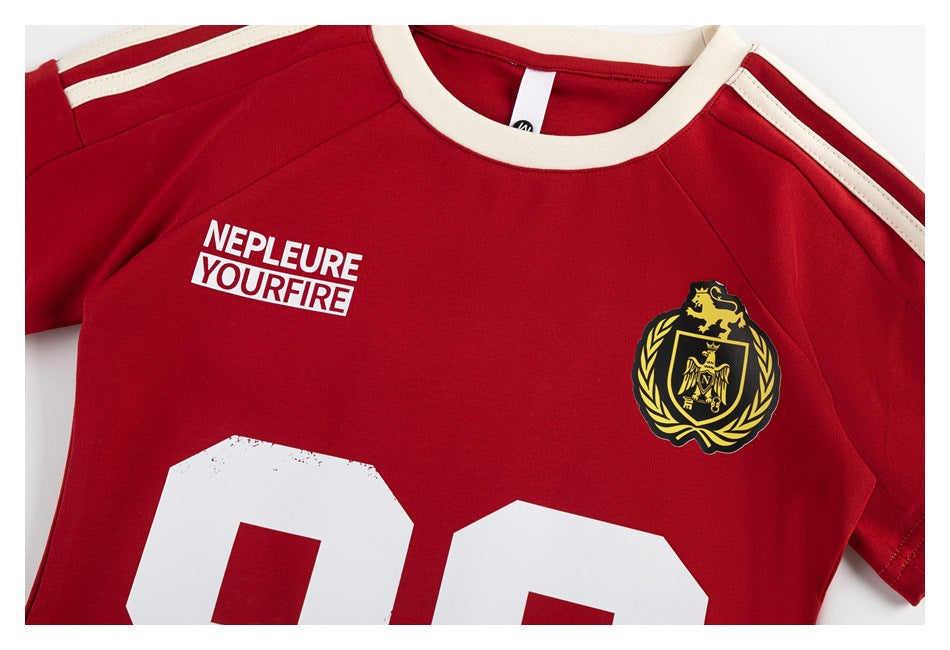 Red jersey front with cream collar and shoulder stripes, white lettering, a gold crest, and part of a large white number.