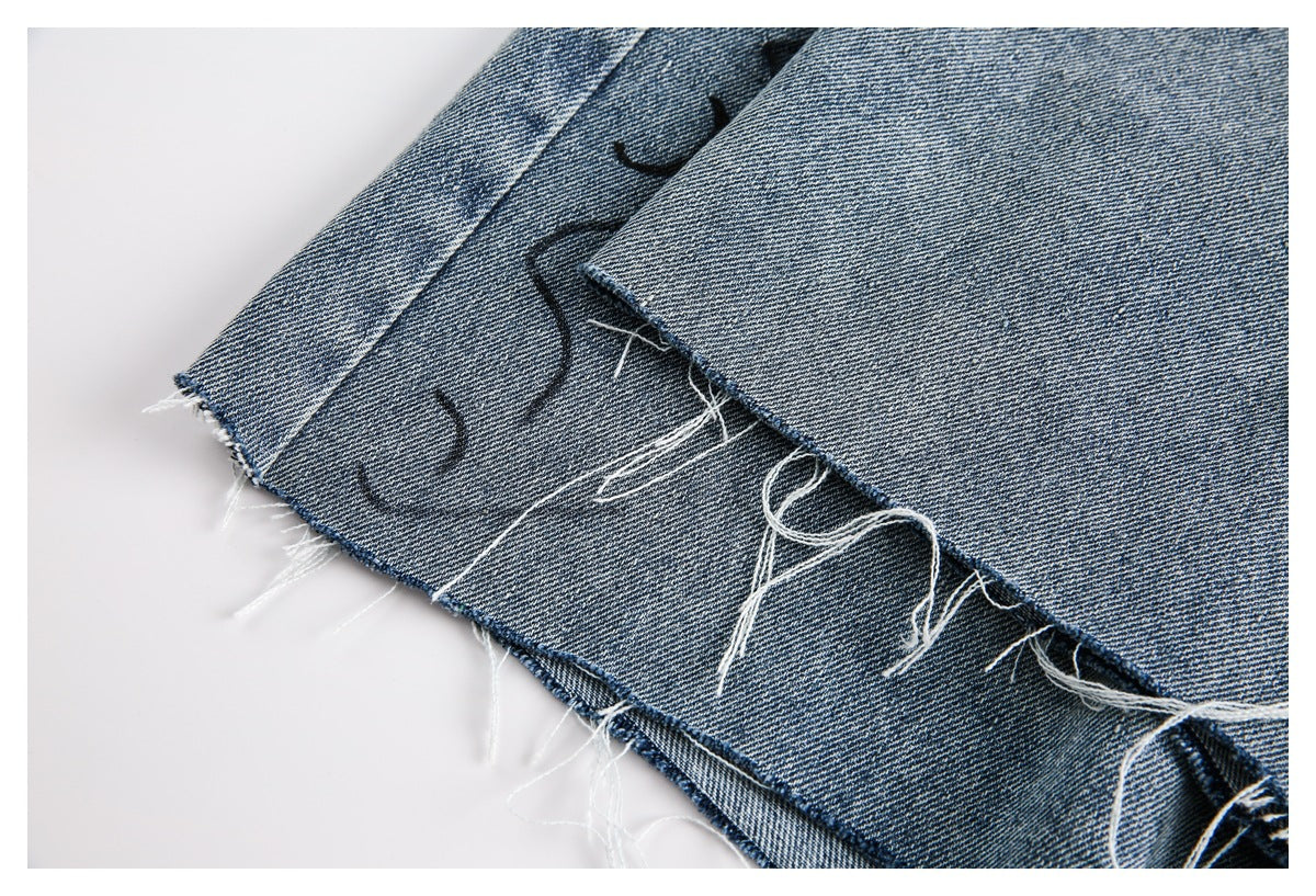 Close-up of layered blue denim with raw, frayed edges and loose white threads.